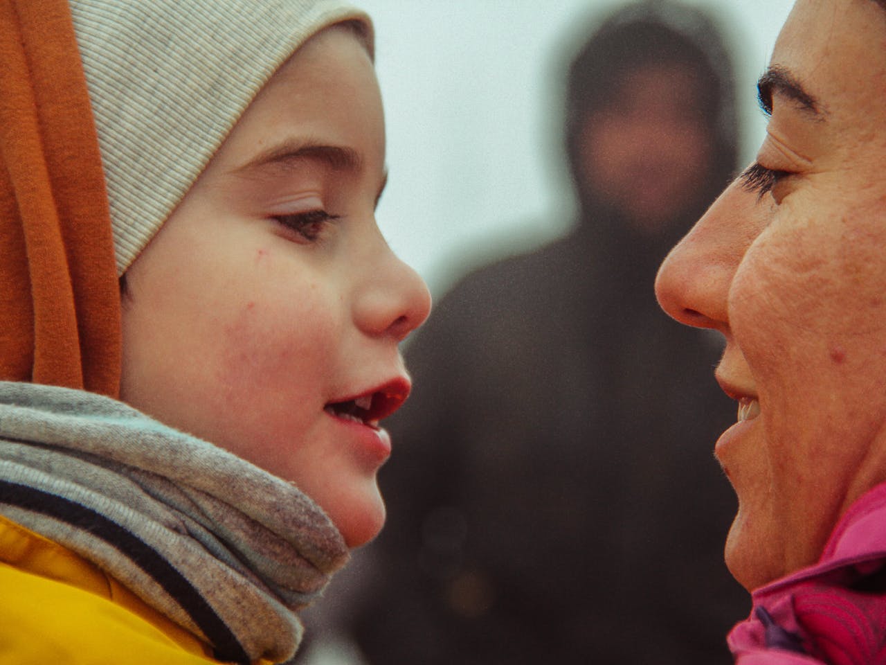 Close-up of mother and child wearing warm clothing, sharing an intimate moment.